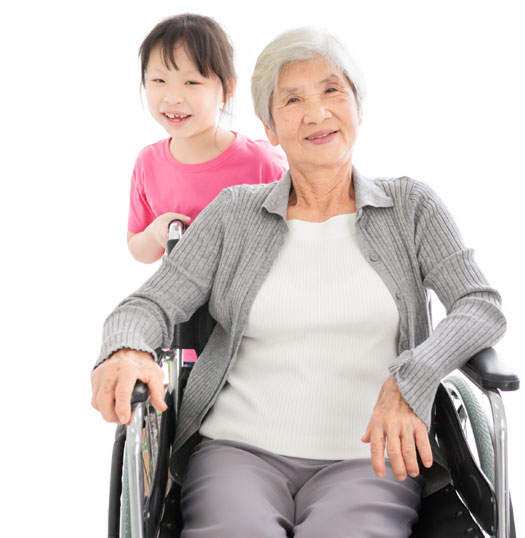 A grandmother in wheelchair with granddaughter overlooking her shoulder