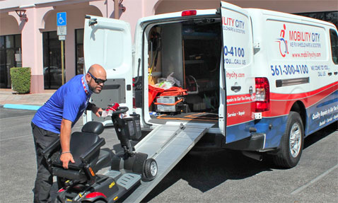 A man loading a wheelchair into a van using a ramp