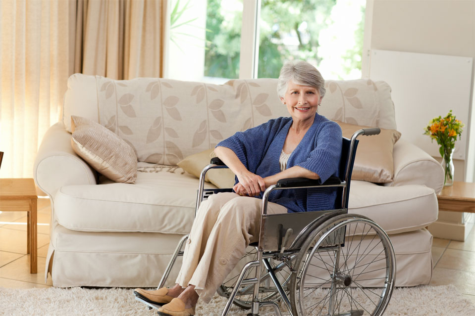 A woman in her wheelchair smiling in her living room