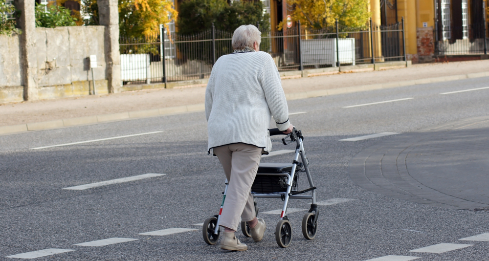 A senior woman pushes her rollator down the street
