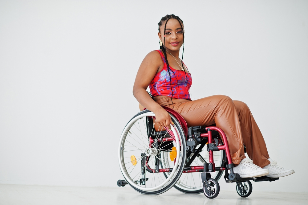 A young woman using a customized red wheelchair with yellow reflectors.