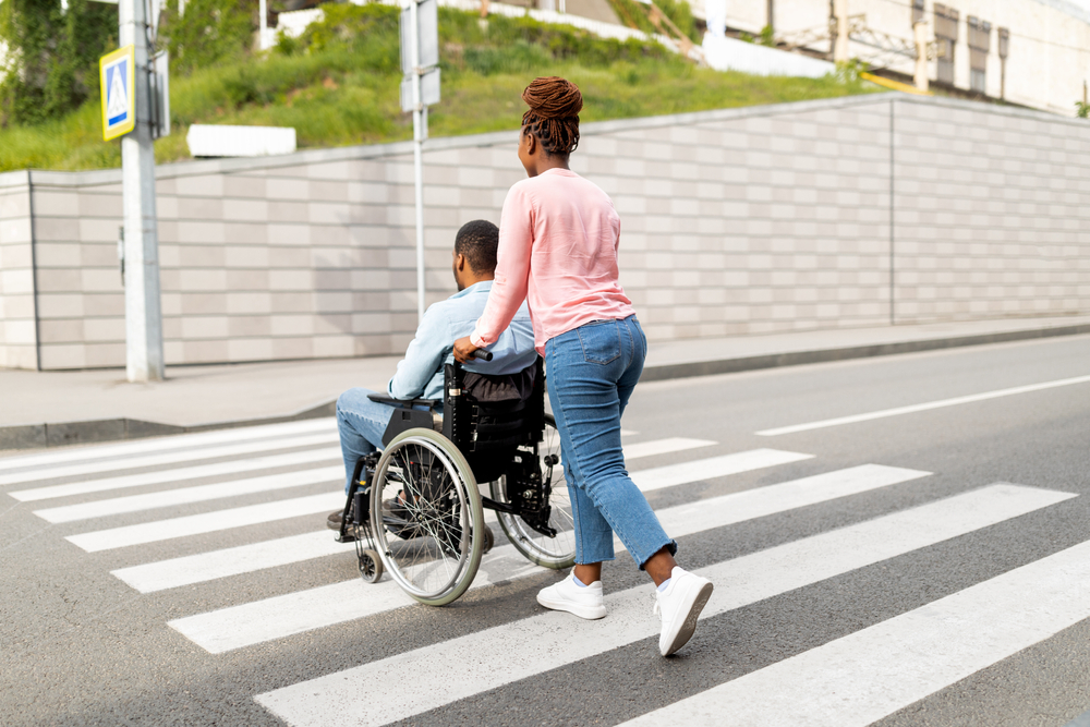 A woman pushes a man in a wheelchair.